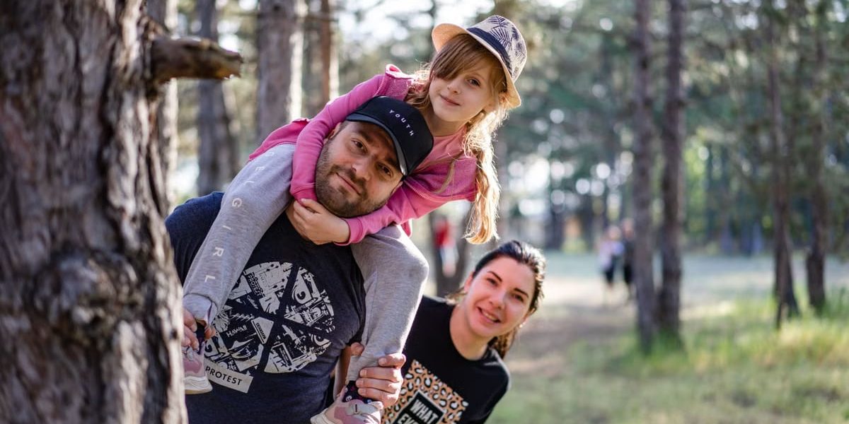 A joyful family enjoying a playful day in a sunlit forest park, capturing the essence of togetherness.