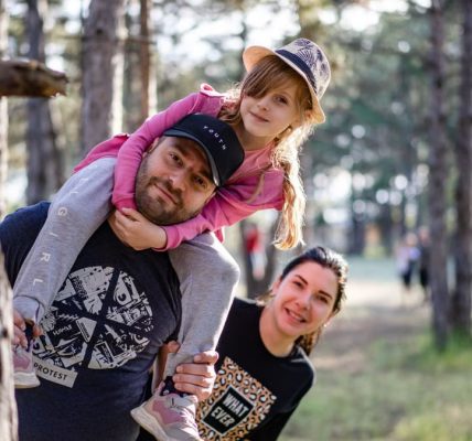A joyful family enjoying a playful day in a sunlit forest park, capturing the essence of togetherness.